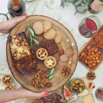 Create-a-food-and-drink-hamper-overhead-wood-round-with-hands-cake-cheese-square-low-1.jpg